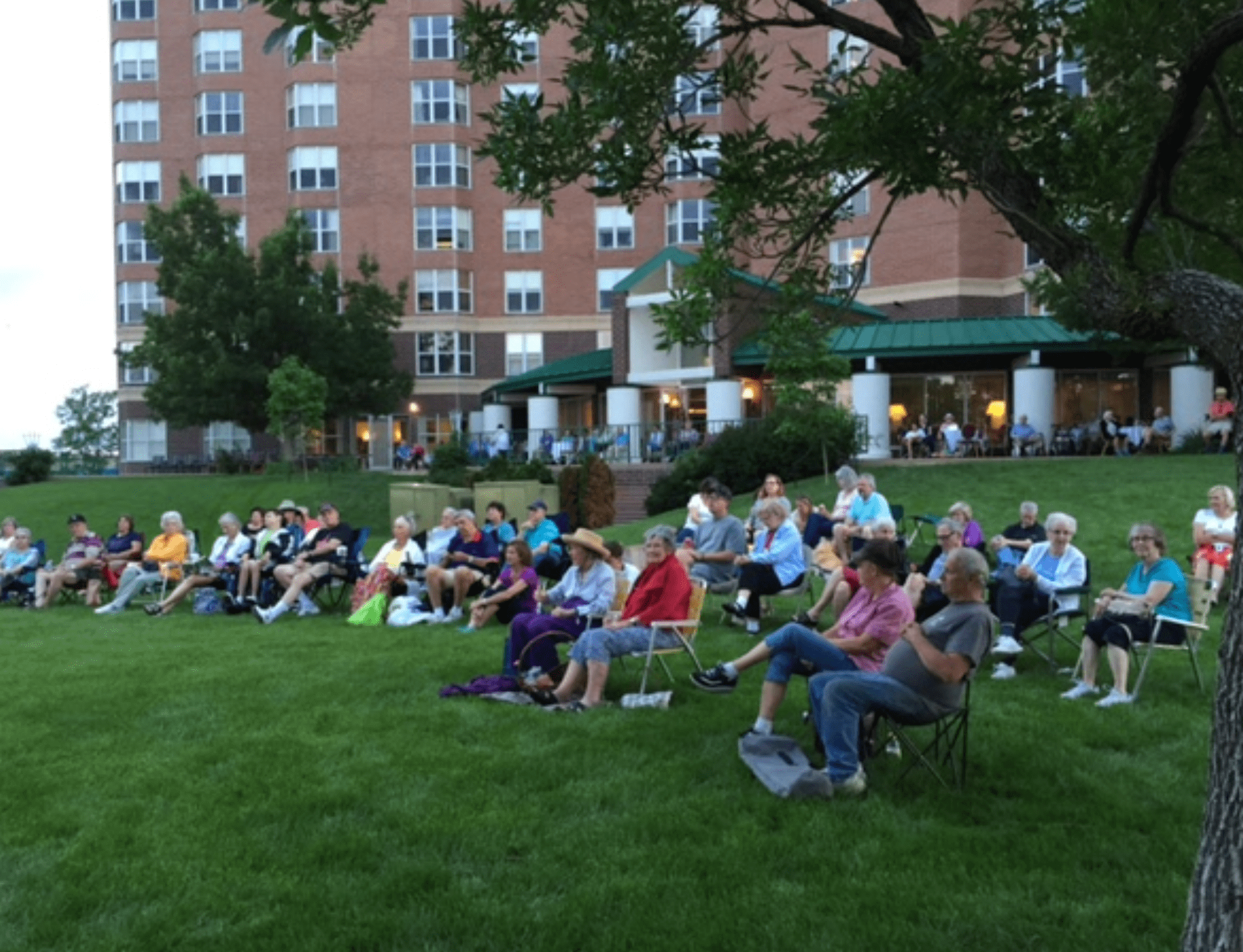 a large group of people sitting on the grass in front of a building