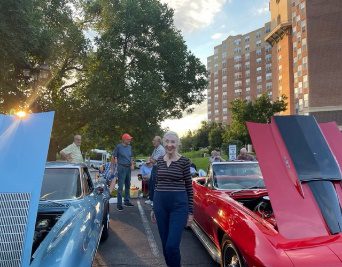 a woman standing next to a group of classic cars