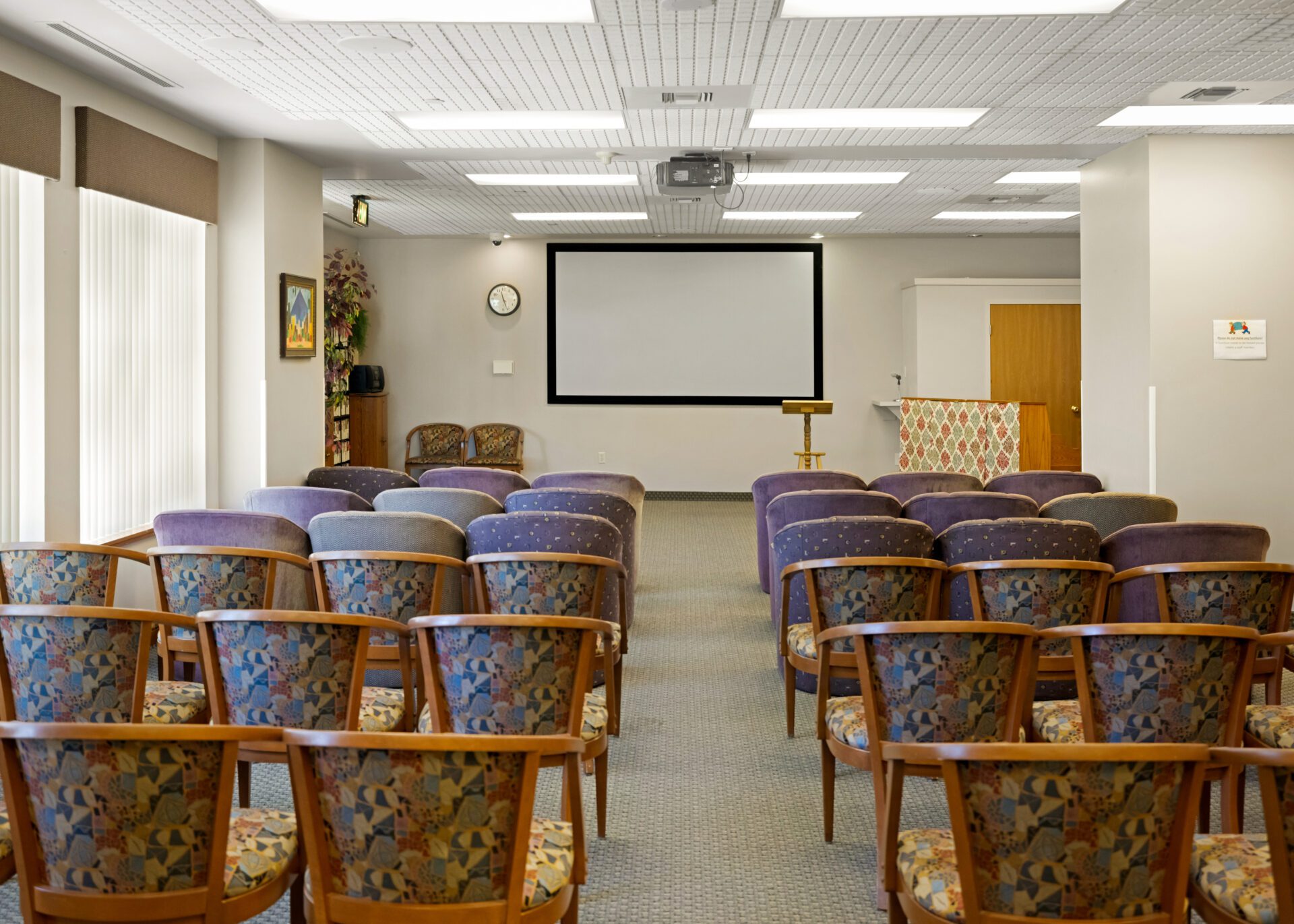 a conference room with rows of chairs and a projector screen