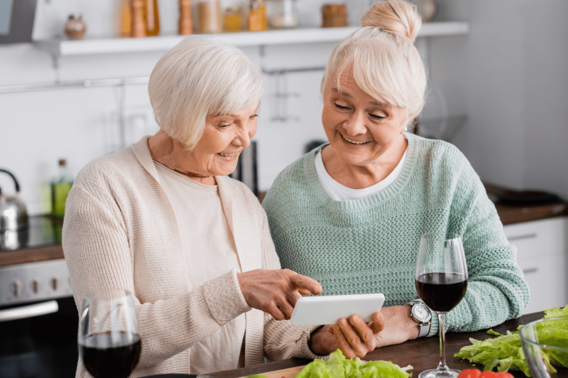 cheerful senior woman pointing with finger at smartphone near retired friend and vegetables on table